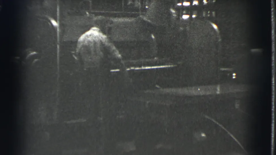 The worker appears partly turned away while handling equipment in the dark industrial interior identified by metadata as Cleveland in 1939.