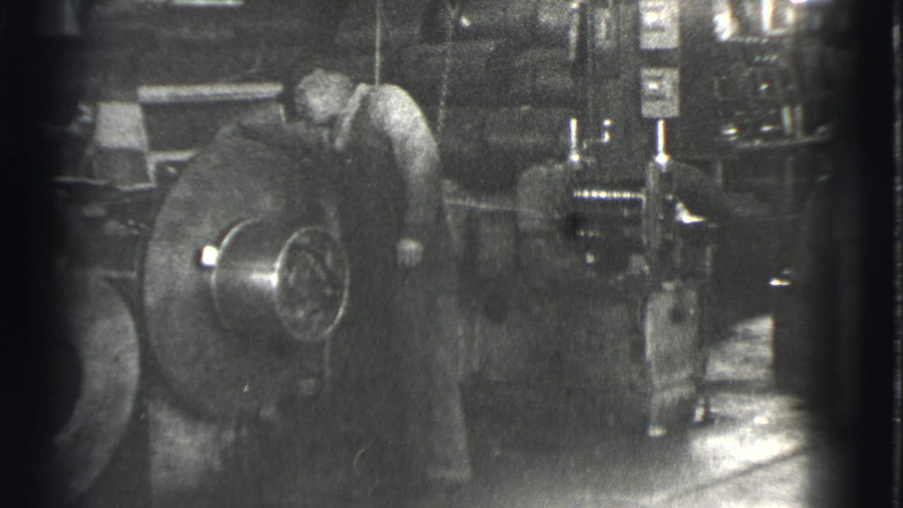 Worker stands close to the round machine with factory equipment behind him.