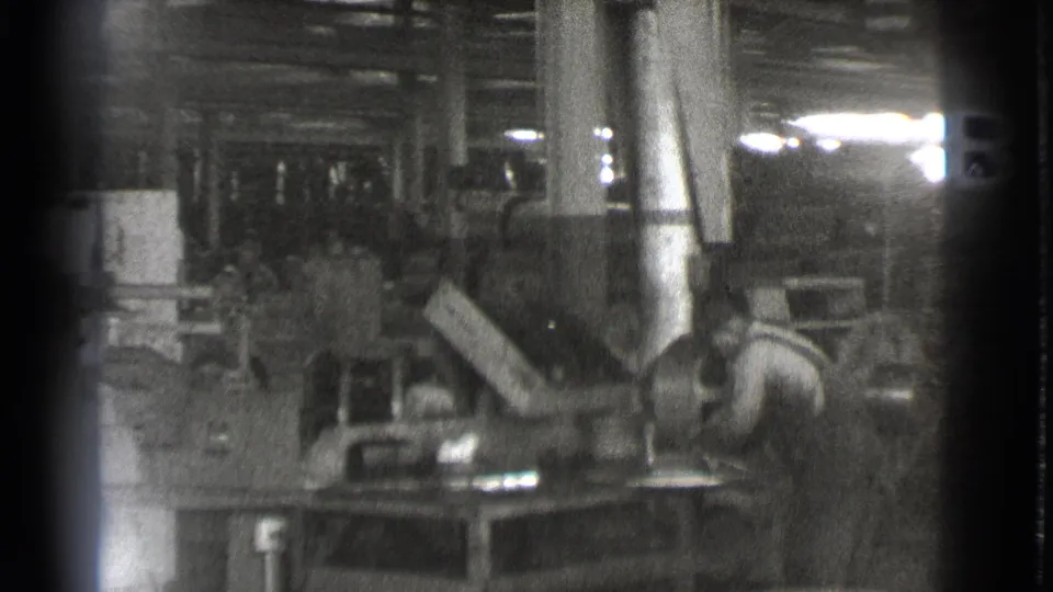 A wider 1939 Cleveland shop-floor view shows workers among large machines, metal ductwork, tables, columns, and overhead industrial structure.