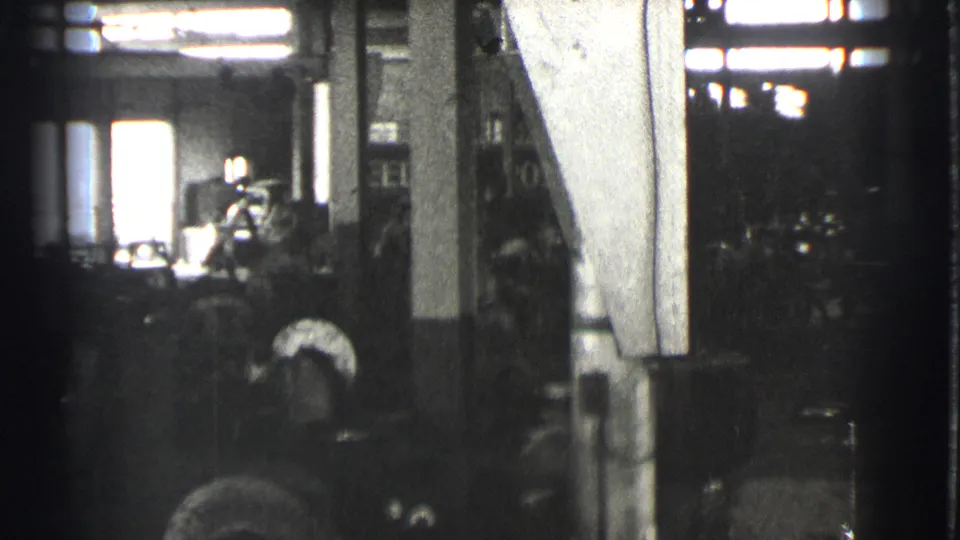 The Cleveland factory scene shows a worker near equipment, strong backlight from windows or a doorway, and machinery across the floor.