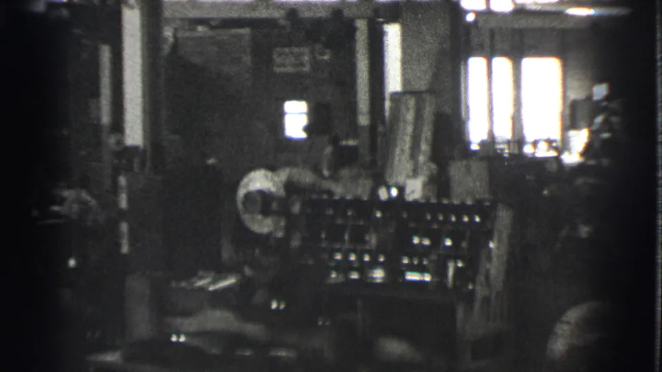 The final frame shows factory machinery, a partly visible worker, columns, windows, and workshop materials in soft 1939 black-and-white 8mm footage.