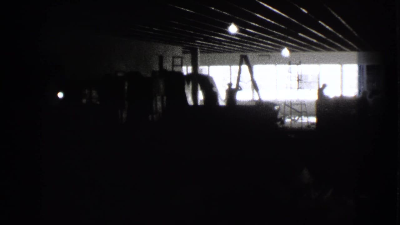 Dim interior with stacked objects silhouetted against bright rear windows.