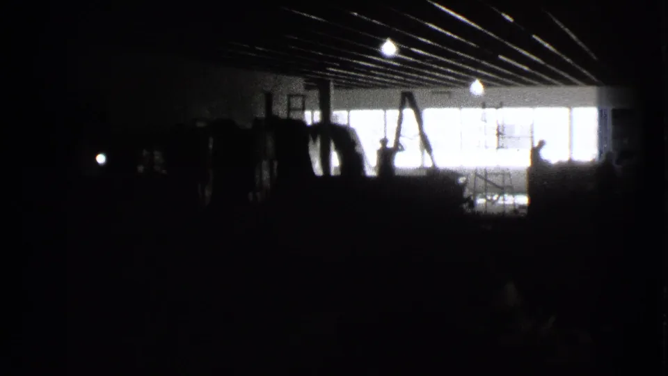 1939 Cleveland home-movie frame showing a dark storage-like interior with stacked wooden objects and bright windows beyond.