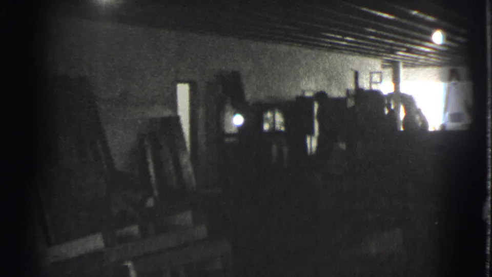 1939 black-and-white frame showing leaning wooden pieces, a possible mirror or frame, and a cluttered storage space.