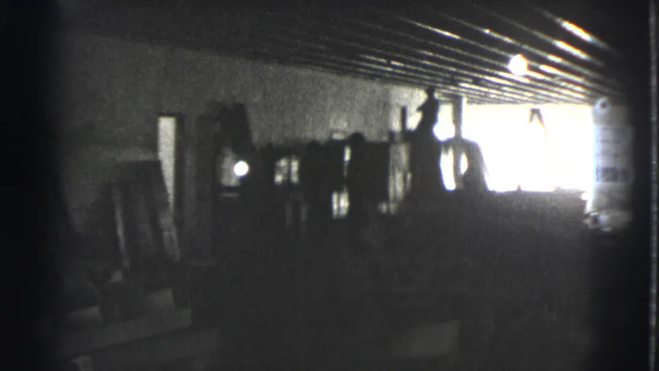 A dark 1939 Cleveland interior appears backlit by a bright doorway or window, with indistinct storage or machinery in the foreground.