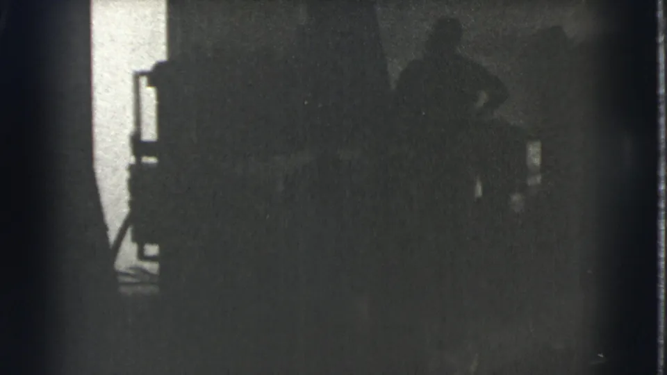 In this 1939 Cleveland 8mm frame, indistinct silhouetted figures stand in a dim interior near a bright window or doorway.