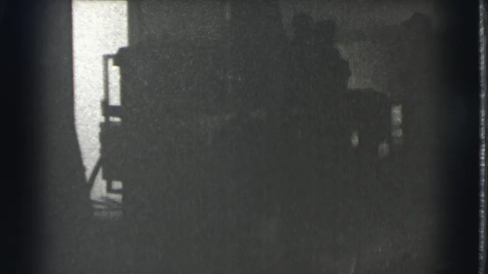 The frame appears to show a standing person in a Cleveland interior, largely reduced to silhouette by low light and dense grain.