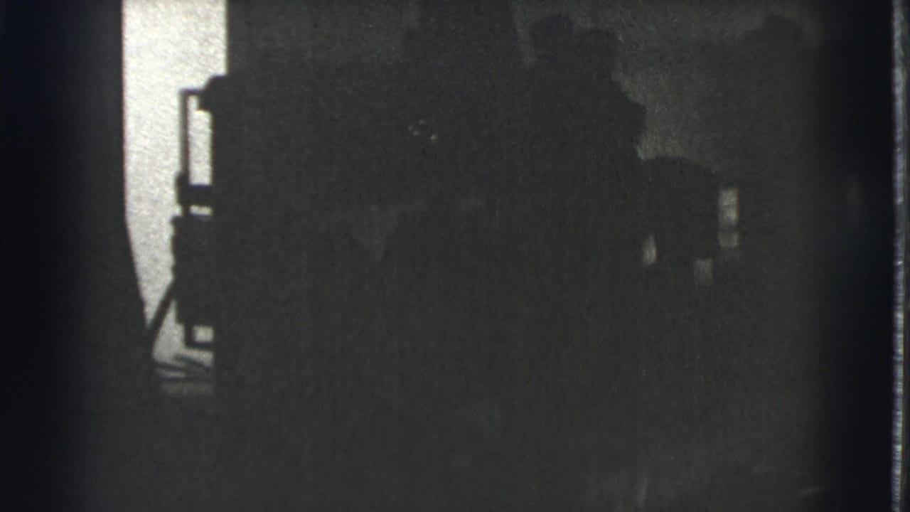 Dark opening frame from a 1939 Cleveland 8mm clip, with only a partial building edge and shadowed exterior shapes visible.