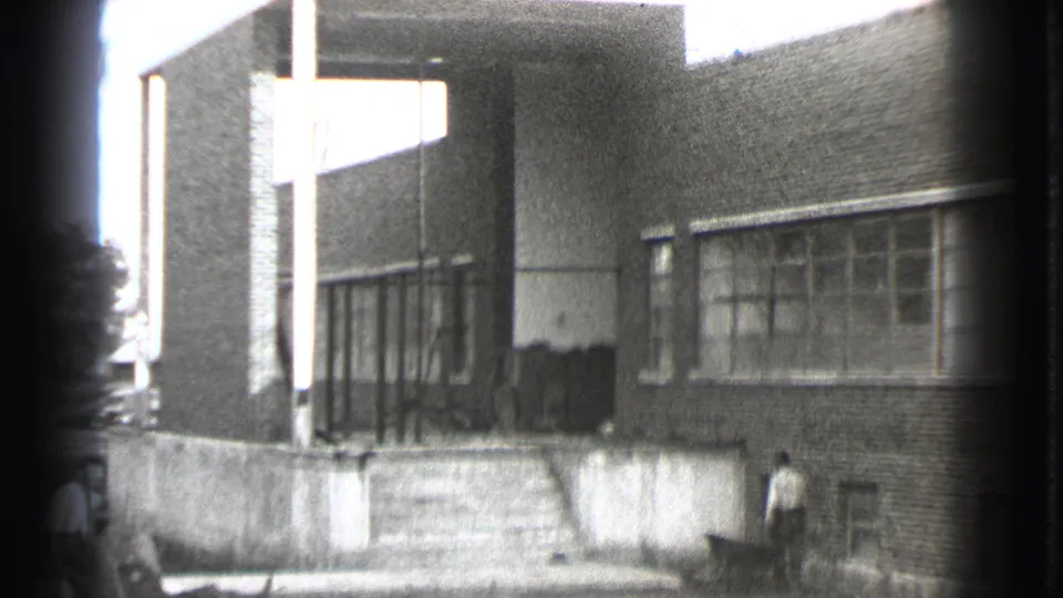 1939 Cleveland view of a brick building exterior with broad windows, a covered entrance, steps, and a man standing near the lower wall.