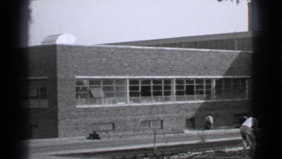 1939 Cleveland 8mm frame showing a brick building with divided windows and a person near the lower right edge.