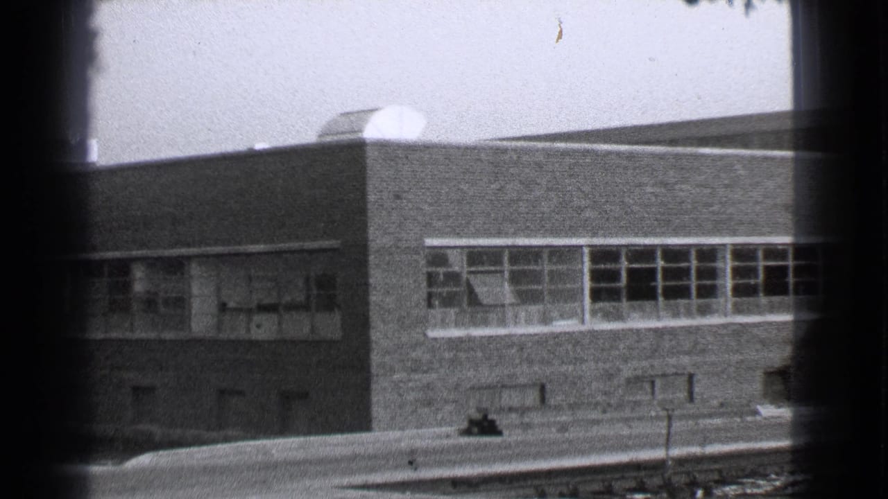 Brick building facade with long rows of windows and dark frame edges.