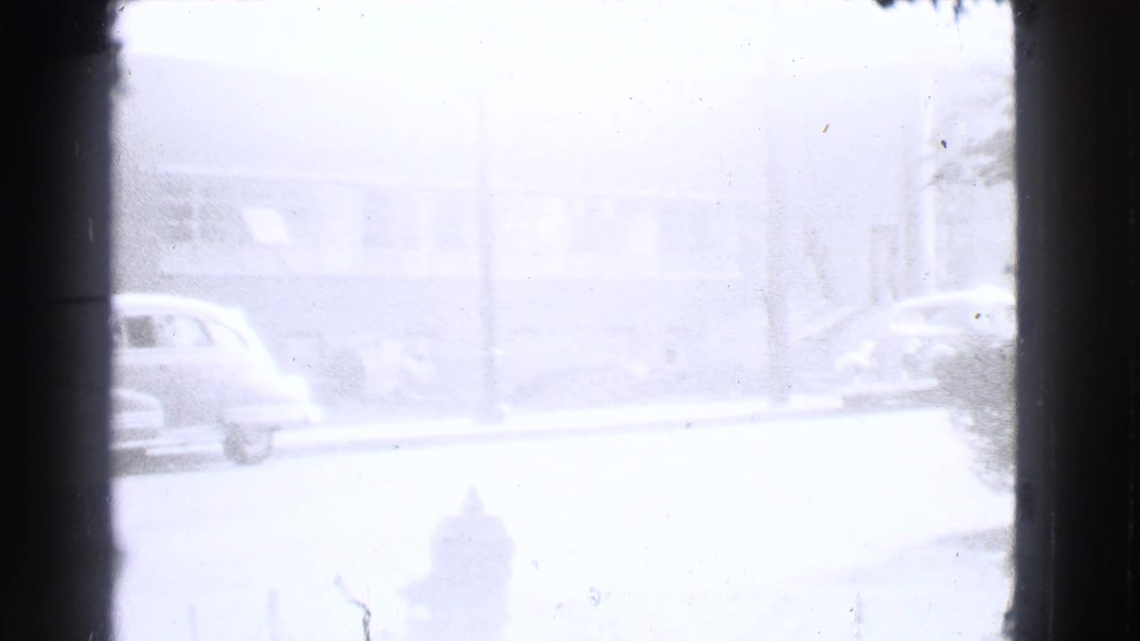 Soft, overexposed 1939 Cleveland street frame showing a parked car, fire hydrant, and building facade beyond the road.