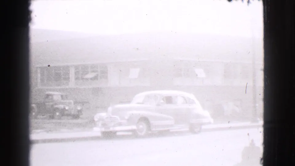1939 Cleveland street view with a rounded sedan parked along the curb outside a long low building.