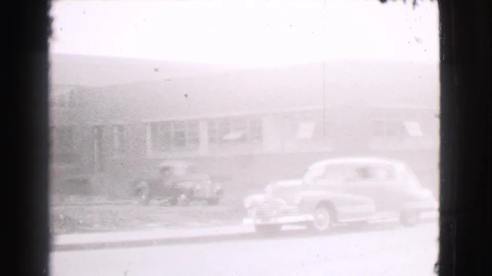 1939 Cleveland curbside scene with parked automobiles and a small truck near a long building frontage.
