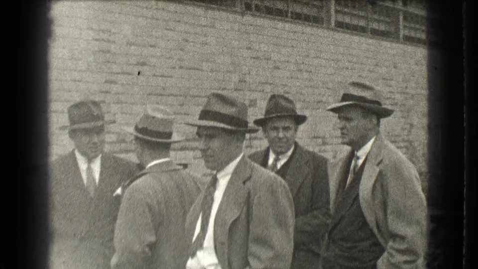 Five adult men in suits, ties, and brimmed hats stand outside a brick building in Cleveland, Ohio, in 1939 home-movie footage.