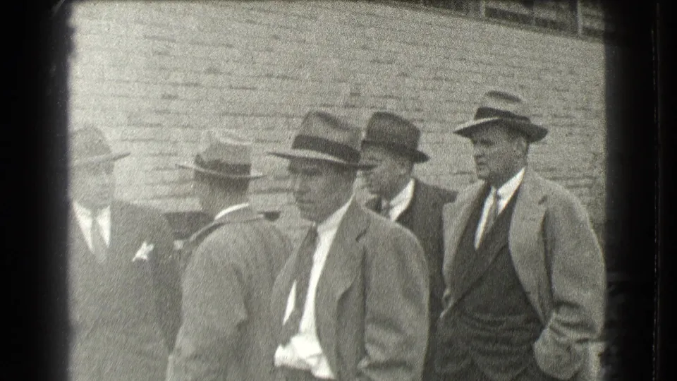 Several suited men in brimmed hats stand in a tight outdoor group against a brick wall, consistent with the Cleveland 1939 clip metadata.