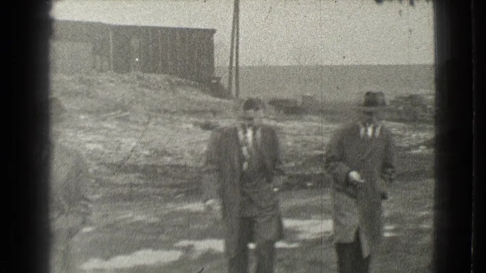 Two suited men walk near the camera in the Cleveland home-movie footage, while the third man is partly outside the frame at left.