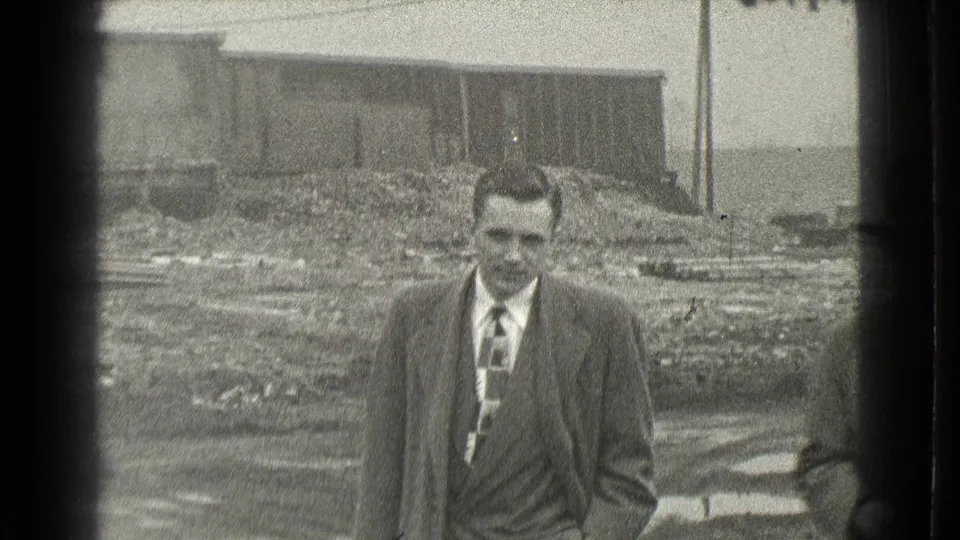 A man in a suit and patterned tie walks toward the camera in the 1939 Cleveland home-movie scene.