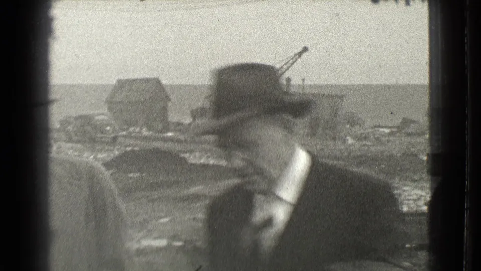 The final frame shows a man in a dark hat and coat turning across the handheld view, with distant industrial structures in Cleveland.