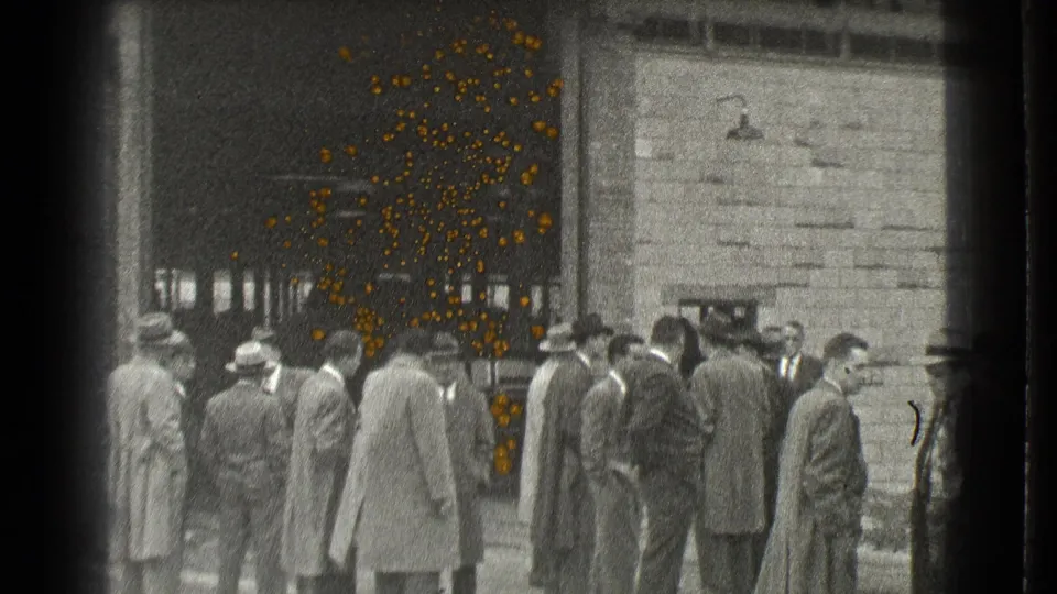 Men in formal coats and hats stand and talk near a dark entrance in 1939 Cleveland home-movie footage.