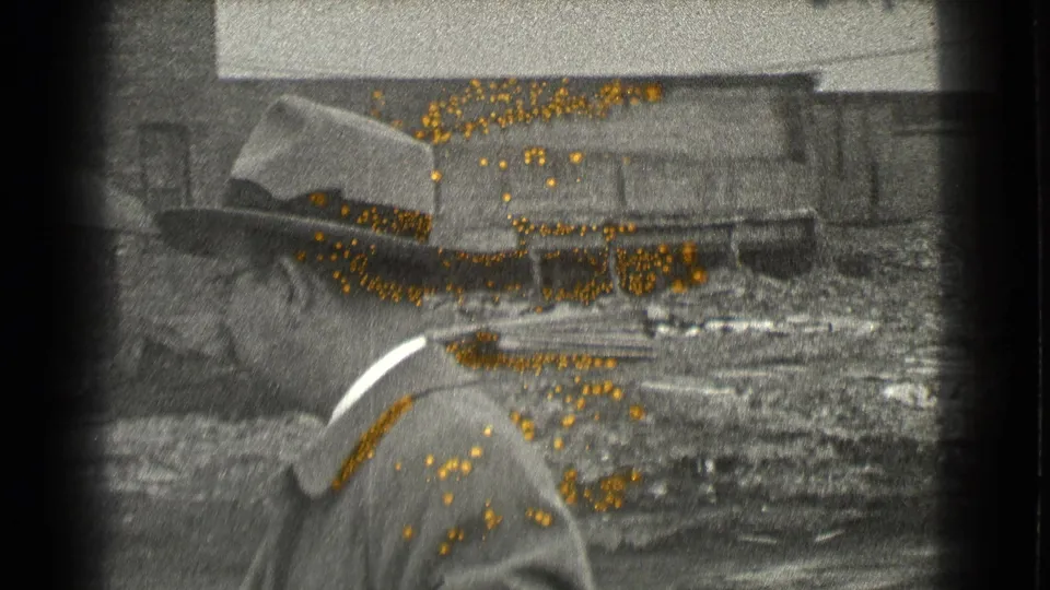 In Cleveland, Ohio in 1939, a suited man in a fedora is filmed in profile against industrial buildings and rough ground.