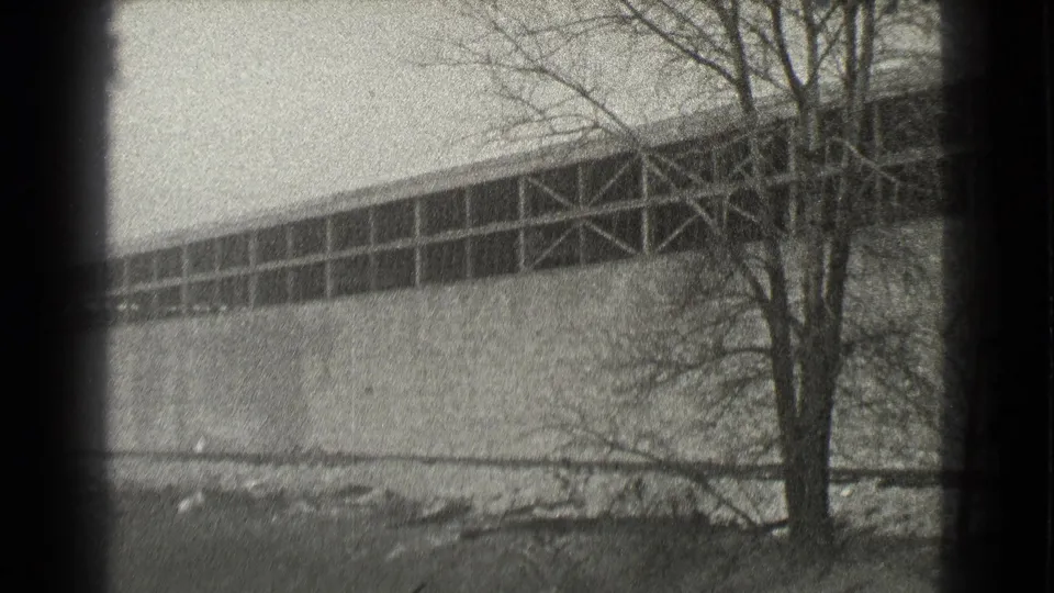 1939 Cleveland frame of the warehouse facade, showing high industrial windows, structural cross-bracing, a bare tree, and snow patches at the base.