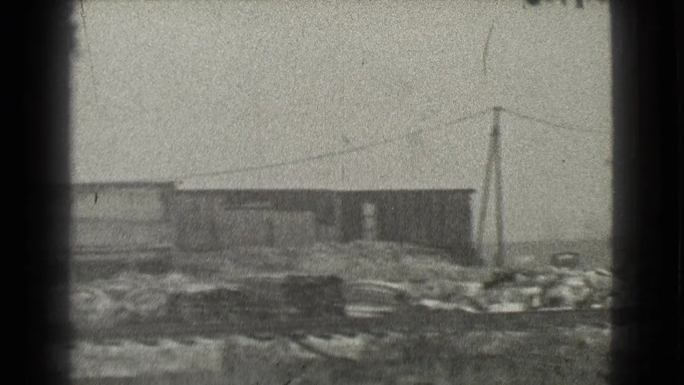 End frame of the 1939 Cleveland industrial yard showing a low building, utility poles, rail tracks, and scattered debris.