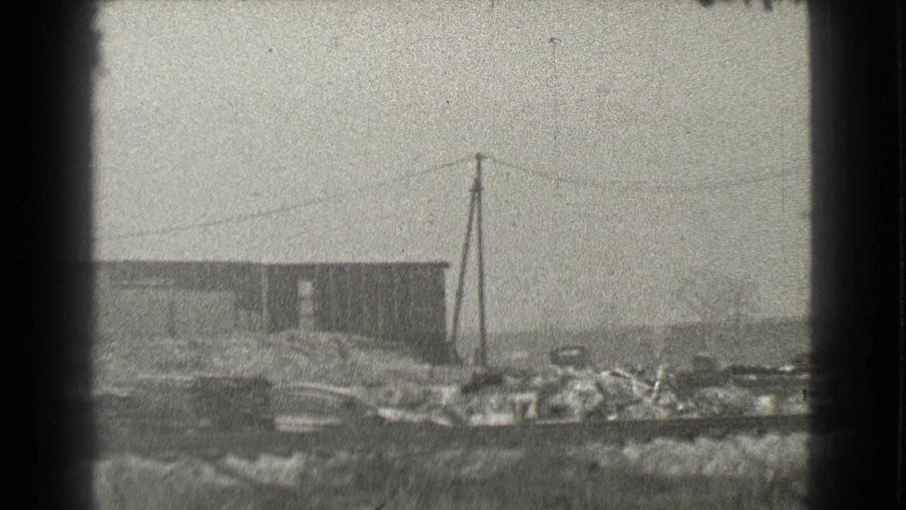 1939 Cleveland 8mm view of a weathered industrial building near rough rail-side ground and power lines.
