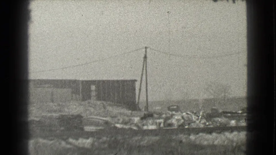 1939 Cleveland 8mm view of a weathered industrial building near rough rail-side ground and power lines.