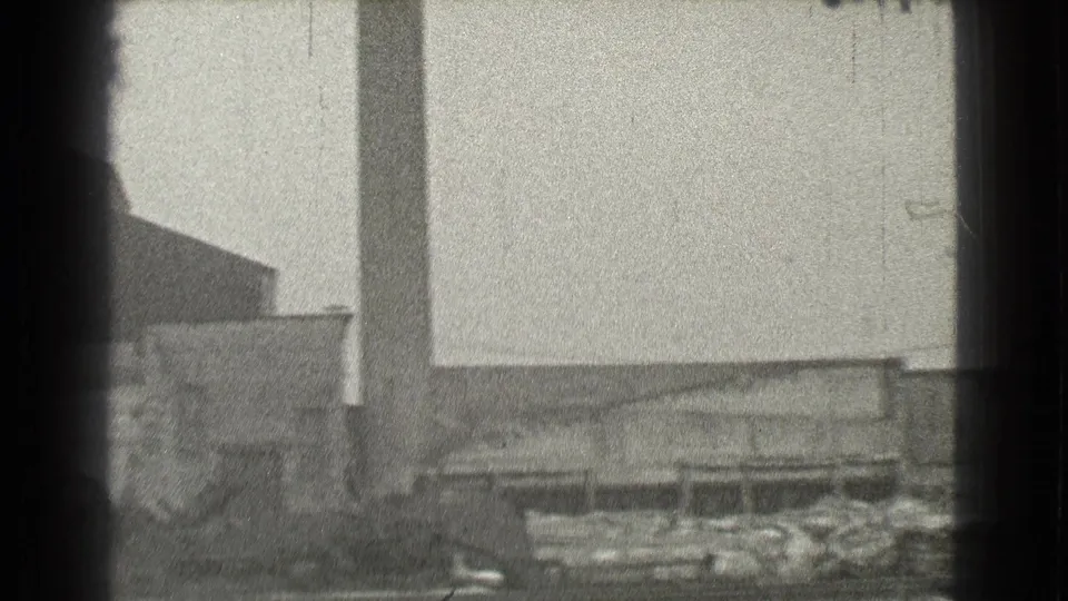 1939 Cleveland industrial exterior with a tall stack or column, low buildings, and debris near the ground.