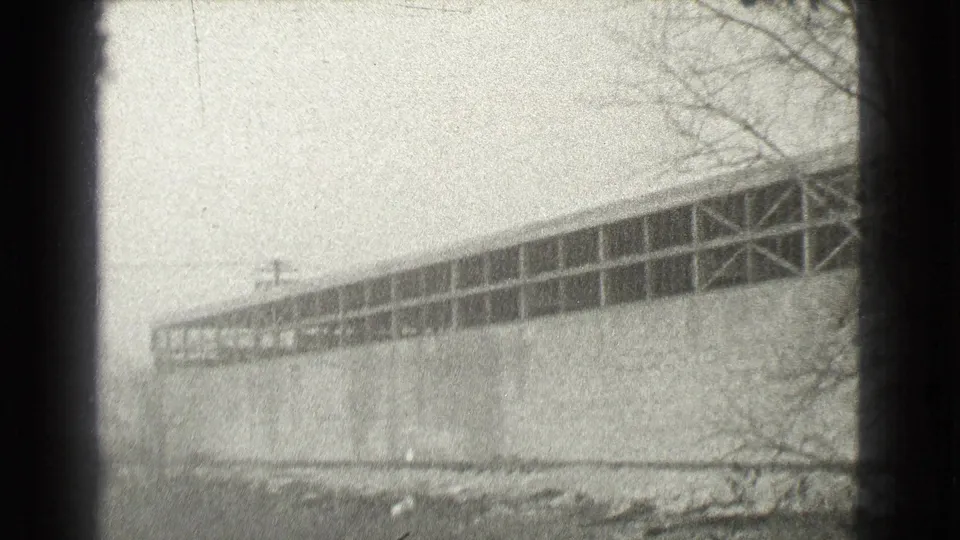 Black-and-white 8mm view of a large Cleveland building exterior with bare trees and open ground nearby.