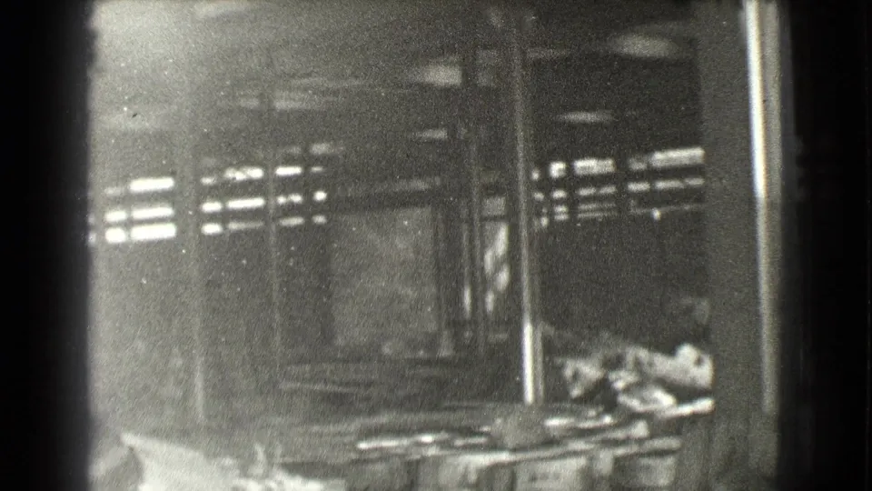 1939 Cleveland frame with a shadowed industrial interior, structural posts, high windows, and indistinct equipment or debris.