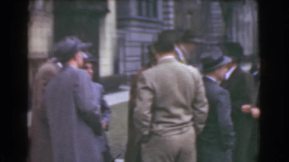 Men in 1930s business attire stand close together on a Cleveland sidewalk outside a stone building.