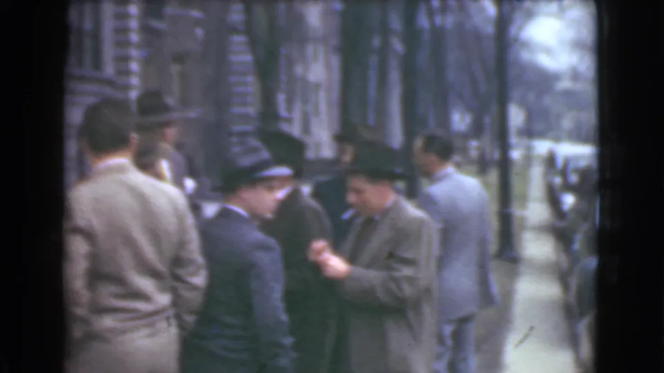 Cleveland sidewalk scene with men in suits and hats near a curb, with a street and bare trees in the background.