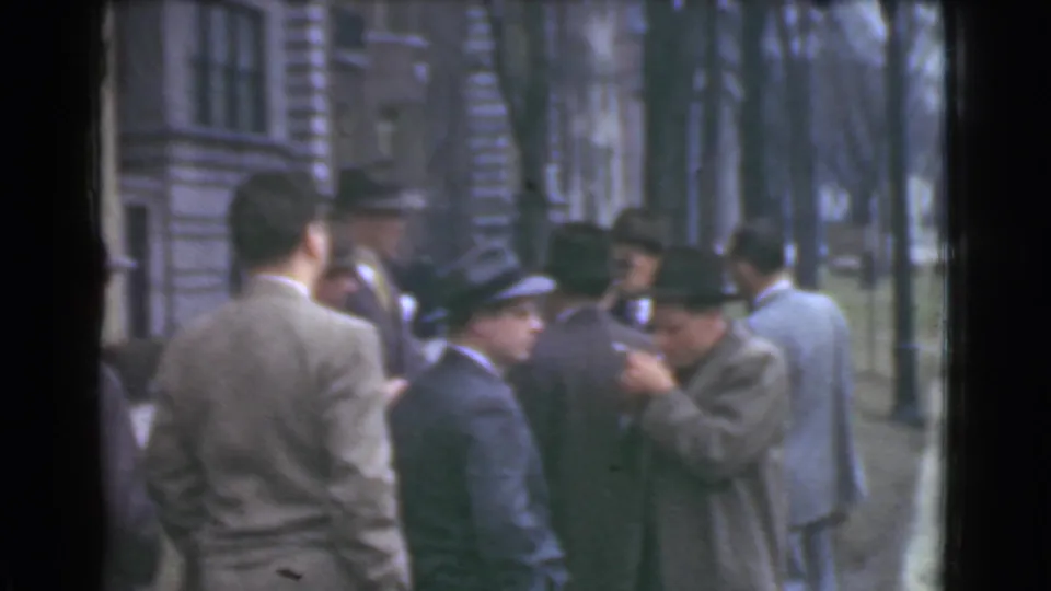 1939 Cleveland home-movie frame of adult men in business dress conversing outside a downtown-looking stone facade.