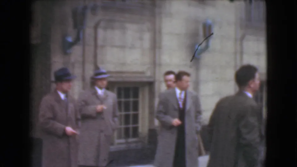 The 1939 Cleveland street scene shows adult men in formal clothing gathered by a stone facade with barred lower windows.