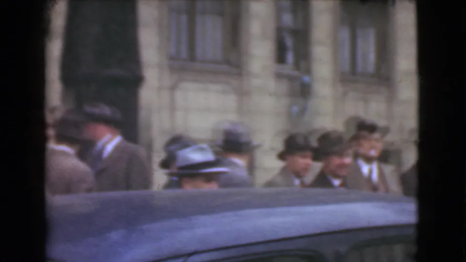 1939 Cleveland street view with suited men in fedoras near a stone building, partly blocked by a dark car roof.