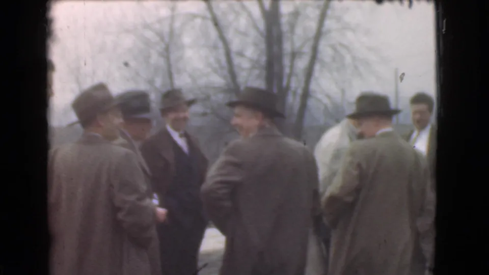 Suited men in 1939 Cleveland appear to converse outdoors, with hats, overcoats, and bare trees visible behind them.