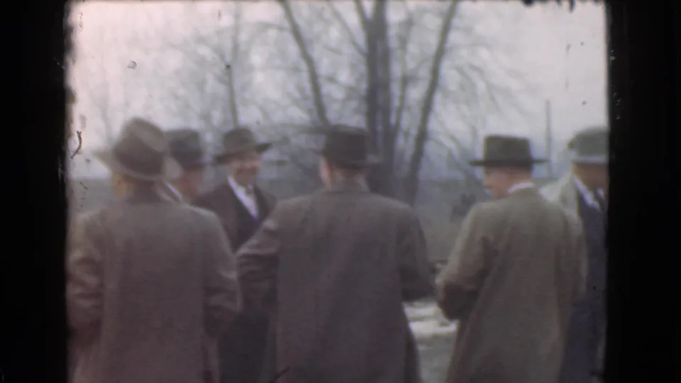 Several suited men, many seen from behind, stand in a loose circle in a Cleveland outdoor setting in 1939 footage.