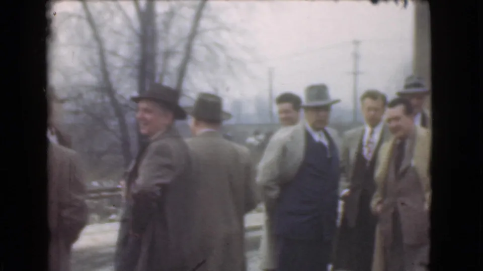 A candid 1939 Cleveland frame shows men in suits and hats standing outdoors, with one man smiling toward the camera.