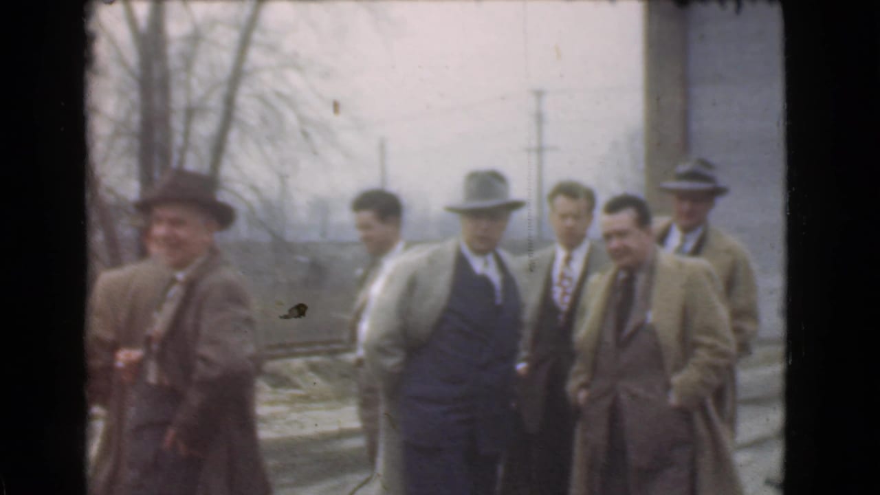 Adult men in suits, overcoats, and fedoras gather outdoors in Cleveland, Ohio, in 1939 home-movie footage.