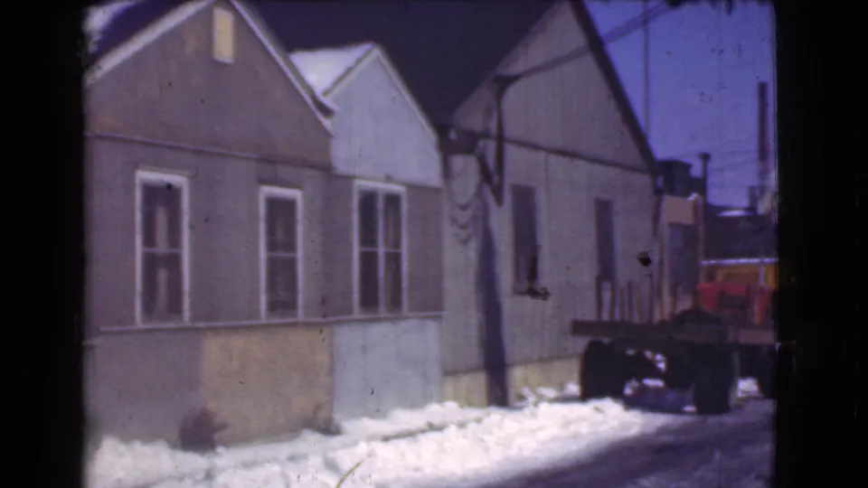 1939 Cleveland home-movie view of modest houses, snow piled along the street, overhead utility lines, and a parked truck.