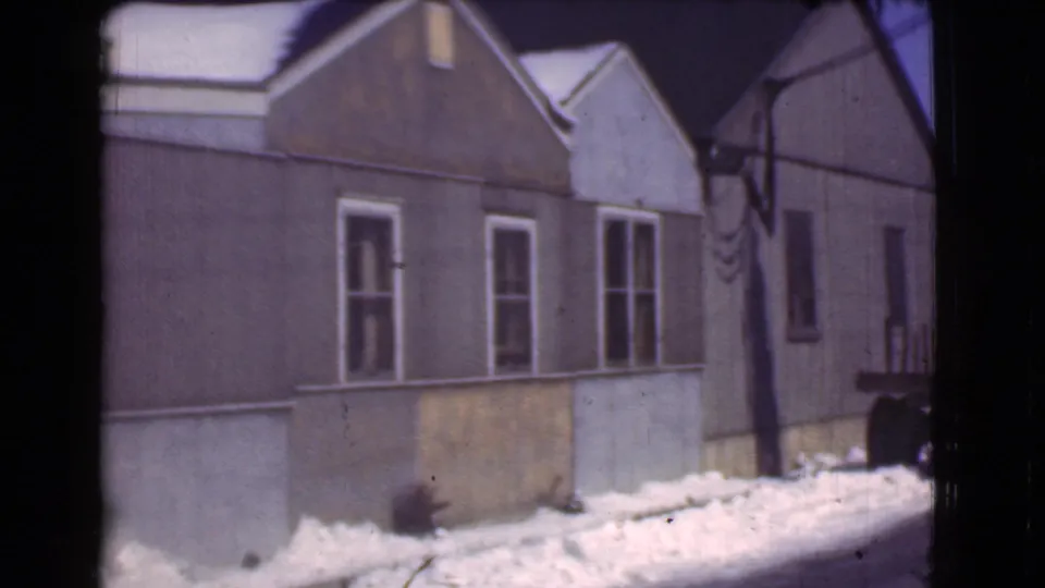 Final 1939 Cleveland frame showing snow along a quiet residential street, narrow houses, utility lines, and part of a truck.