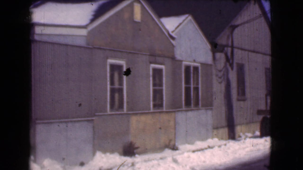1939 Cleveland 8mm frame showing a modest brown house with white-trimmed windows and snowbanks along the base.