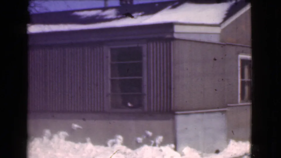 Final 1939 Cleveland frame of the pan, showing a side wall with a dark window, brown siding, foundation, and snow at ground level.