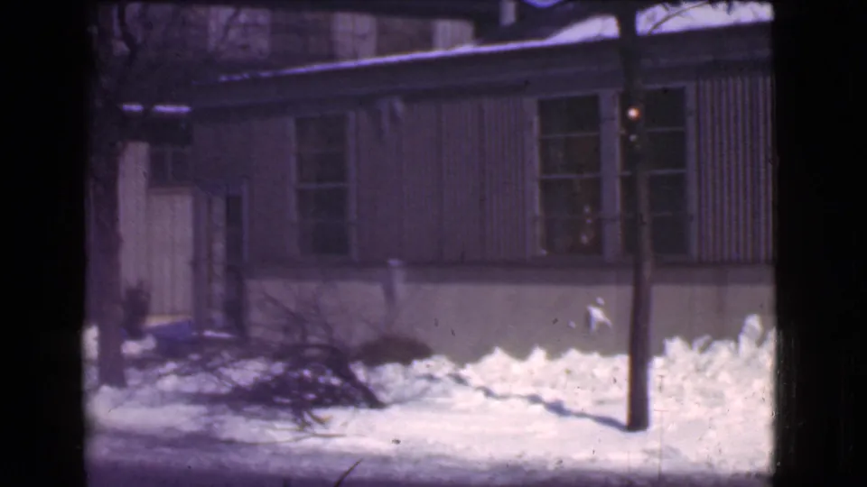 1939 Cleveland winter street view with snow piled near a modest building, bare branches, and a pole in the foreground.