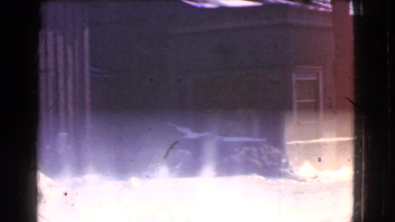 Bright snowbank and dark storefront facade with a window at the right edge.