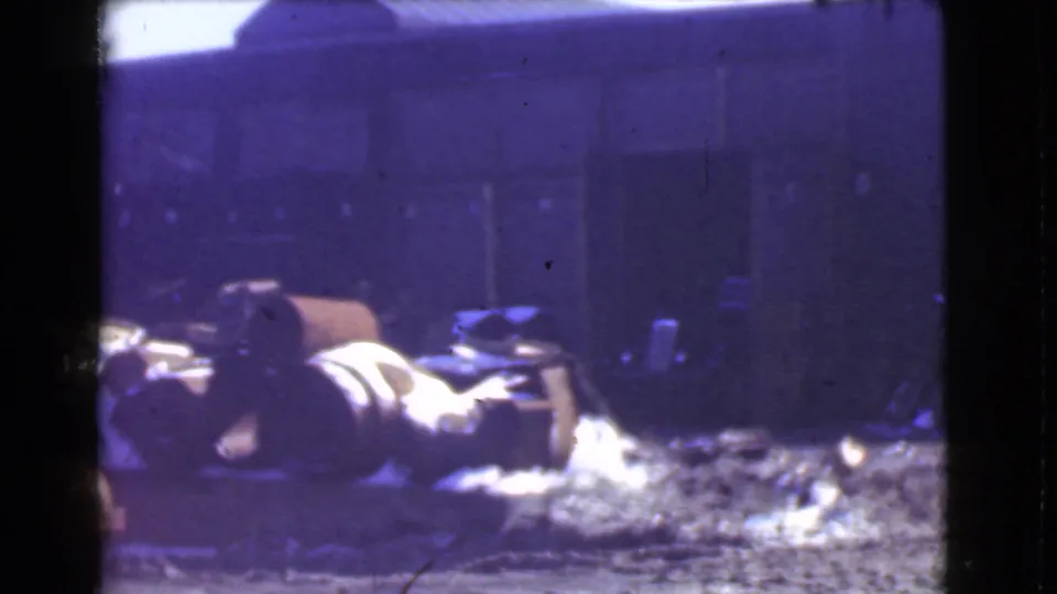 1939 Cleveland 8mm view of a cluttered industrial yard, with barrels, scattered material, and muddy snow-covered ground.
