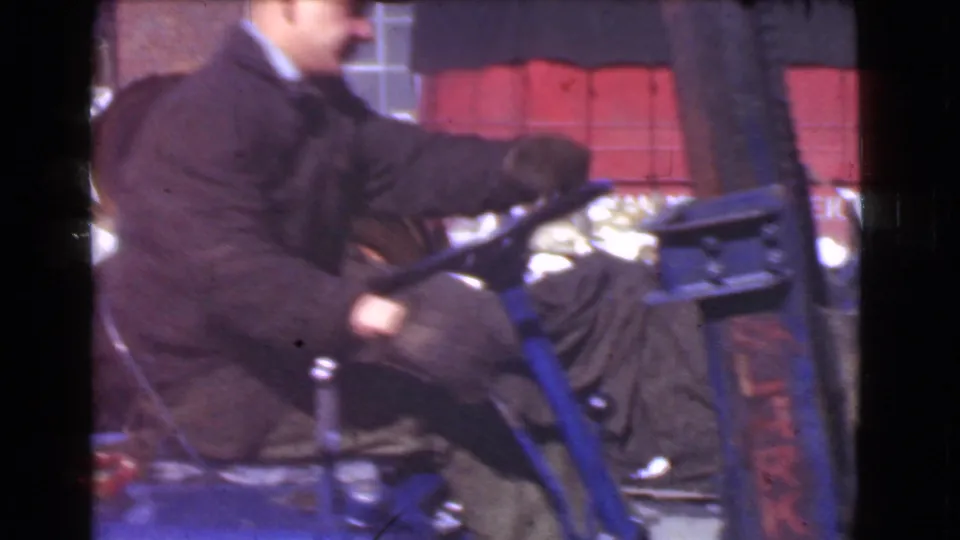 Side view of the forklift operator shifting or steering near stacked red materials in the 1939 Cleveland industrial footage.