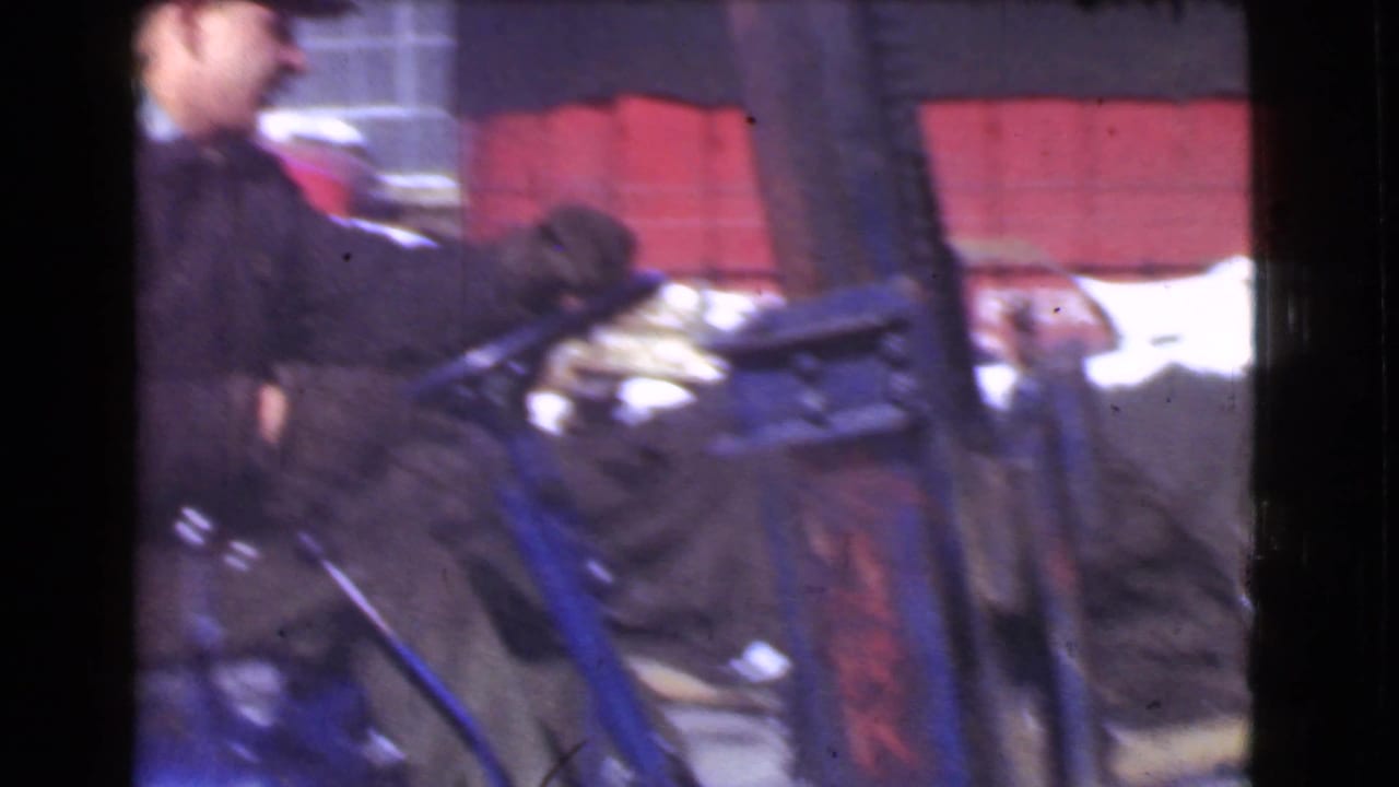 Worker at the controls of a forklift or industrial vehicle beside stacked red materials.